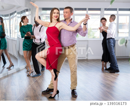 Woman enjoying passionate Latin American dancing with male partner in dance hall Woman enjoying passionate Latin American dancing with male partner in dance hall 139316173