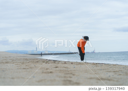 砂浜でゴミ拾いをする人 139317940