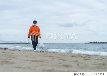 砂浜でゴミ拾いをする人 139317941