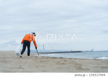 砂浜でゴミ拾いをする人 砂浜でゴミ拾いをする人 139317944