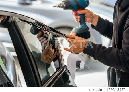 A car wrapping specialist applies a polyurethane film to the car. Detailer PPF A car wrapping specialist applies a polyurethane film to the car. Detailer PPF 139318472