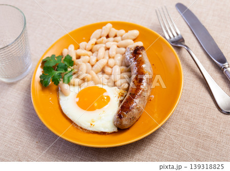 Portion of breakfast food is fried egg and pork sausage with stewed beans Portion of breakfast food is fried egg and pork sausage with stewed beans 139318825