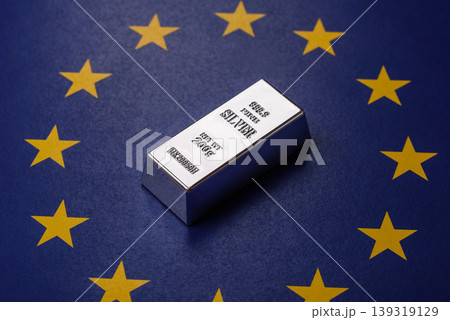 A silver bar, white metal against a backdrop of EU flag, as a concept. A silver bar A silver bar, white metal against a backdrop of EU flag, as a concept. A silver bar 139319129