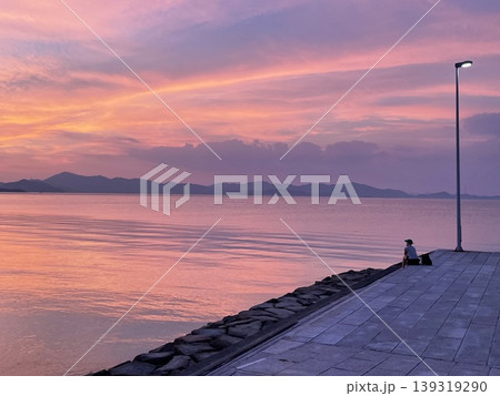 瀬戸内海・豊島の海辺で夕焼けを眺める静かなひととき 139319290