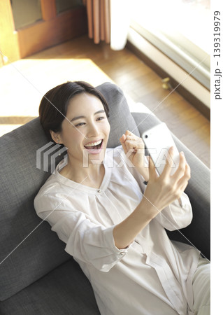 スマートフォンを見る女性 自宅でくつろぐ時間 スマートフォンを見る女性 自宅でくつろぐ時間 139319979