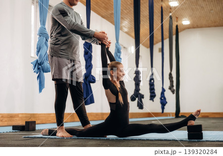Man is teaching. Male instructor assisting a child during yoga practice in a fitness studio 139320284