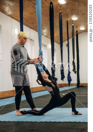 Man is teaching. Male instructor assisting a child during yoga practice in a fitness studio 139320285
