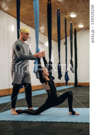 Man is teaching. Male instructor assisting a child during yoga practice in a fitness studio 139320286