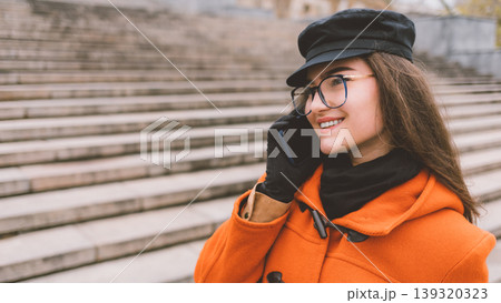 Smiling woman in glasses talks phone on urban steps Smiling woman in glasses talks phone on urban steps 139320323