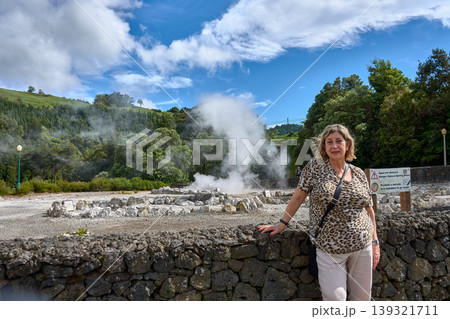 Mature woman smiling and posing in front of the volcanic fumaroles of Furnas in the Azores 139321711