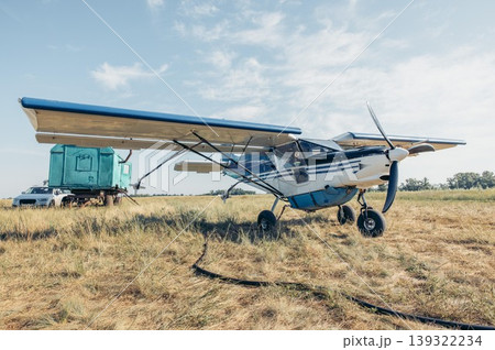 small agricultural aircraft standing on dry field ready for crop spraying. farming aviation equipment in rural landscape on sunny day. agriculture and food production concept 139322234
