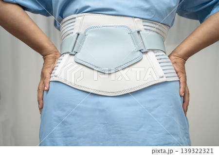 Asian senior pain back wearing elastic support belt with walker. 139322321