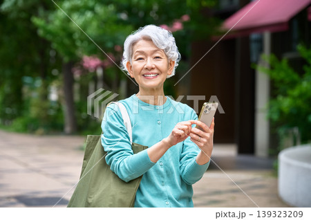 スマートフォンを持ち笑顔のシニア女性 139323209