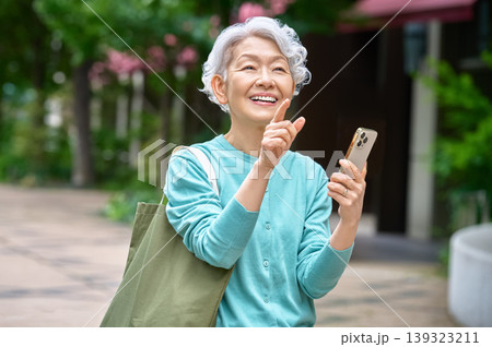 スマートフォンを持ちポーズをとって笑顔のシニア女性 139323211