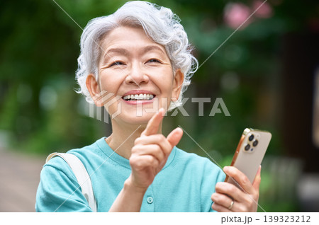 スマートフォンを手に指を立てて笑うシニア女性のクローズアップ 139323212