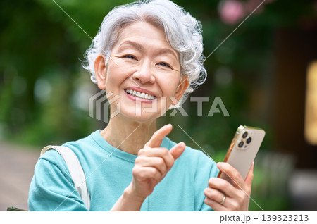 スマートフォンを手に明るく笑うシニア女性のクローズアップ 139323213