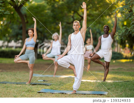 Group of multinational people practitioner performing Garudasana in garden Group of multinational people practitioner performing Garudasana in garden 139324933
