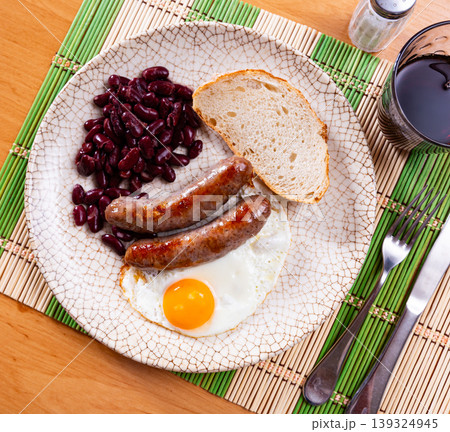 Portion of breakfast food is fried egg and pork sausage with stewed beans Portion of breakfast food is fried egg and pork sausage with stewed beans 139324945