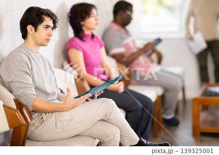 Young guy sitting in a queue at a modern office 139325001