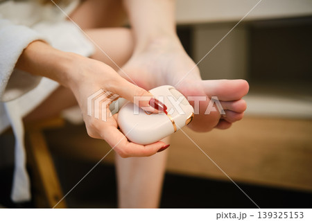 Close-up view of peeling rough skin of ball of the foot with electric exfoliation device Close-up view of peeling rough skin of ball of the foot with electric exfoliation device 139325153