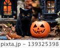 A black cat wearing a witch hat sits on an orange pumpkin, holding a magic wand.. Concept: Playful Halloween Cat 139325398