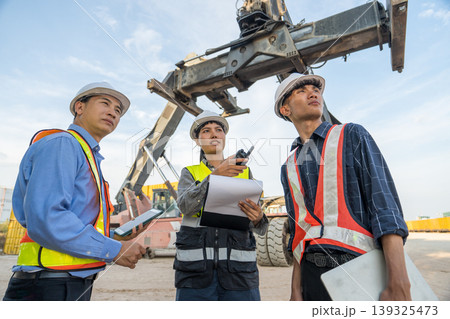 Asian Logistics Manager Pointing at Reach Stacker Crane for Thailand Port Operations Training Asian Logistics Manager Pointing at Reach Stacker Crane for Thailand Port Operations Training 139325473
