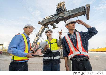 Asian Logistics Manager Pointing at Reach Stacker Crane for Thailand Port Operations Training Asian Logistics Manager Pointing at Reach Stacker Crane for Thailand Port Operations Training 139325474