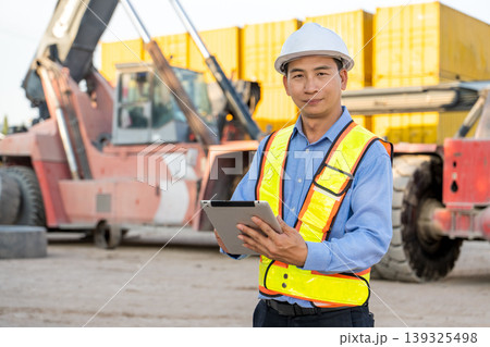 Asian Logistics Supervisor Standing with Tablet by Reach Stacker in Thailand Port Site Asian Logistics Supervisor Standing with Tablet by Reach Stacker in Thailand Port Site 139325498