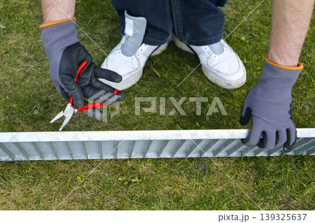 Maintenance task of a metal outdoor drain grate, focusing on proper safety gear and careful handling. Maintenance task of a metal outdoor drain grate, focusing on proper safety gear and careful handling. 139325637
