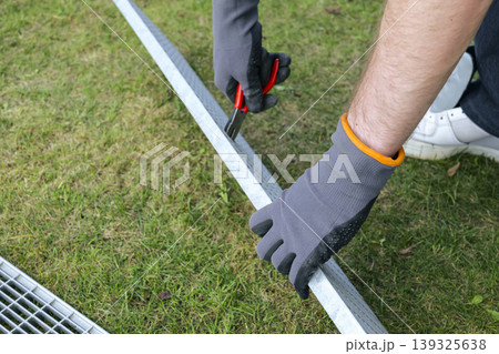 A person wearing gloves holds a pliers during a drain grate maintenance, focusing on proper safety gear and careful handling A person wearing gloves holds a pliers during a drain grate maintenance, focusing on proper safety gear and careful handling 139325638