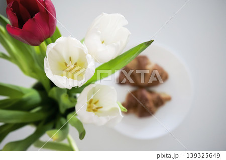 White and red tulips in a vase and croissants on a plate in the background  139325649
