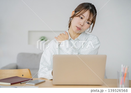 リビングでパソコン作業しながら肩こりに悩む女性 リビングでパソコン作業しながら肩こりに悩む女性 139326568