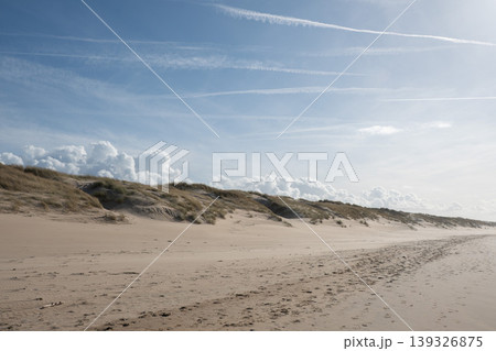 Wide sandy beach with dunes, tracks under blue sky with clouds along North Sea coast in Belgium. Travel destination, tourism marketing, coastal landscape, outdoor recreation, nature background Wide sandy beach with dunes, tracks under blue sky with clouds along North Sea coast in Belgium. Travel destination, tourism marketing, coastal landscape, outdoor recreation, nature background 139326875