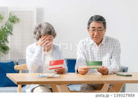 通帳を見て考えるシニア夫婦 通帳を見て考えるシニア夫婦 139327989