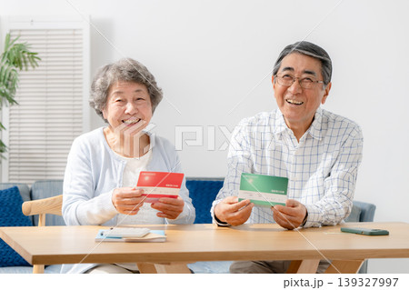 通帳を見て笑顔のシニア夫婦 通帳を見て笑顔のシニア夫婦 139327997