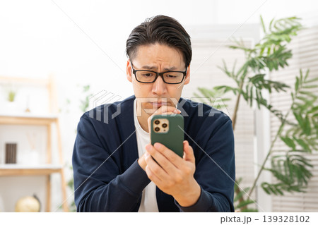 スマホを見て悩む男性 139328102