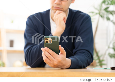 スマホを見て悩む男性　手元 139328107