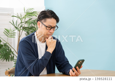 スマホを見て悩む男性 スマホを見て悩む男性 139328111