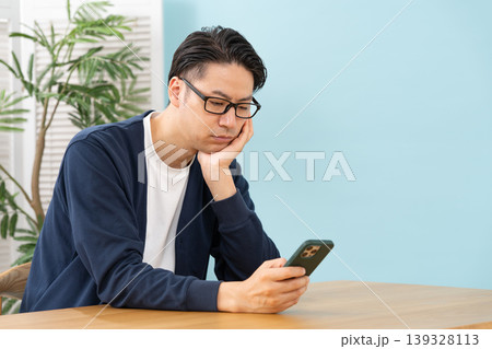 スマホを見て悩む男性 スマホを見て悩む男性 139328113
