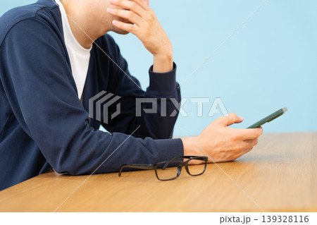 スマホを見て悩む男性 手元 横向き スマホを見て悩む男性 手元 横向き 139328116