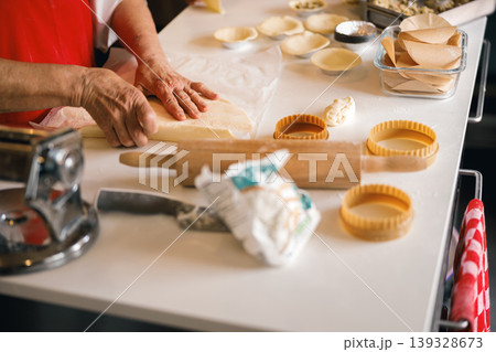 Close up of hands pressing dough on a floured table with baking tools nearby Close up of hands pressing dough on a floured table with baking tools nearby 139328673