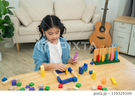 Child Engaged in Creative Play with Colorful Blocks and Toys on Table in Bright Indoor Space with Guitar in Background and Cozy Furniture Child Engaged in Creative Play with Colorful Blocks and Toys on Table in Bright Indoor Space with Guitar in Background and Cozy Furniture 139329109