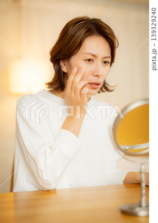 夜の寝室で肌の調子を気にする女性 139329240