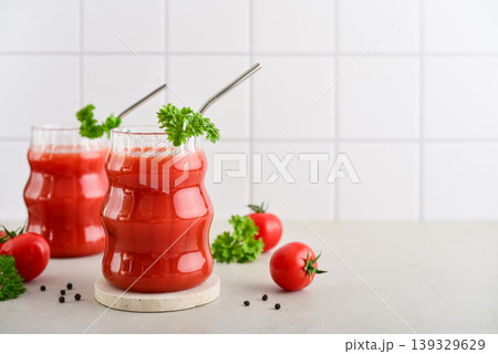 Two glasses of fresh tomato juice with metal straws garnished with parsley and cherry tomatoes Two glasses of fresh tomato juice with metal straws garnished with parsley and cherry tomatoes 139329629