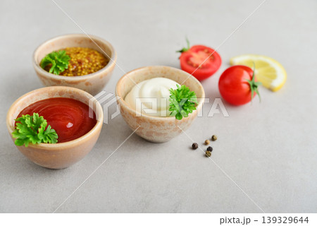 Three small bowls with mayonnaise, ketchup, and mustard a light background Three small bowls with mayonnaise, ketchup, and mustard a light background 139329644