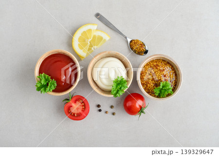 Top view of three small bowls with mayonnaise, ketchup, and mustard arranged in a row on a light background Top view of three small bowls with mayonnaise, ketchup, and mustard arranged in a row on a light background 139329647