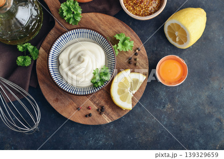 Top view of homemade mayonnaise in a bowl on a wooden board with fresh ingredients Top view of homemade mayonnaise in a bowl on a wooden board with fresh ingredients 139329659