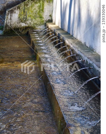 Multiple spouts streaming fresh water into stone channel Multiple spouts streaming fresh water into stone channel 139330046