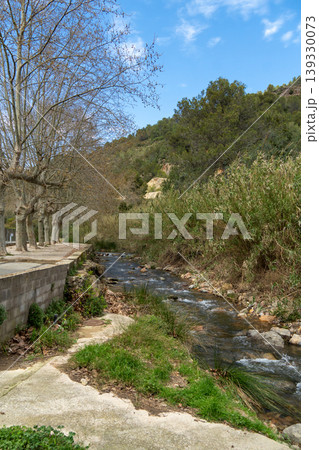 River flowing along concrete path with trees River flowing along concrete path with trees 139330073
