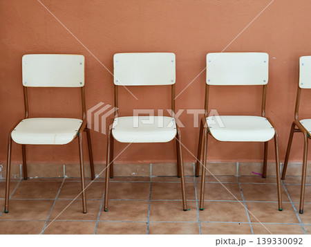 Empty chairs lining wall symbolizing waiting and anticipation 139330092